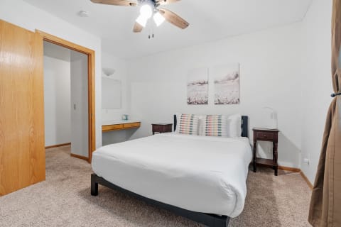Cozy bedroom with a bed, nightstand, and artwork on the wall.