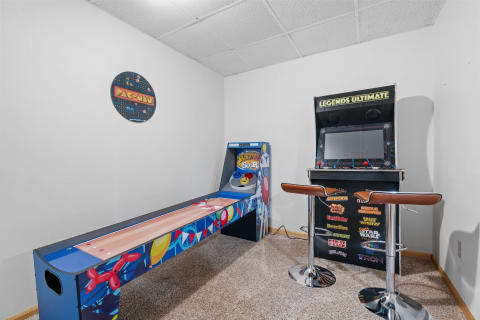 A game room corner with a Skee-Ball machine and an arcade console displaying classic game titles.