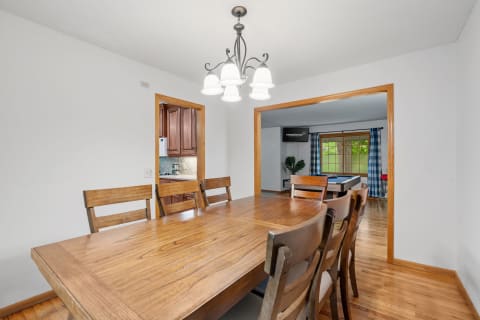 A spacious dining room with a wooden table and access to a living area beyond.