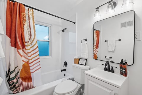 A bright and modern bathroom with a colorful shower curtain and elegant black fixtures.