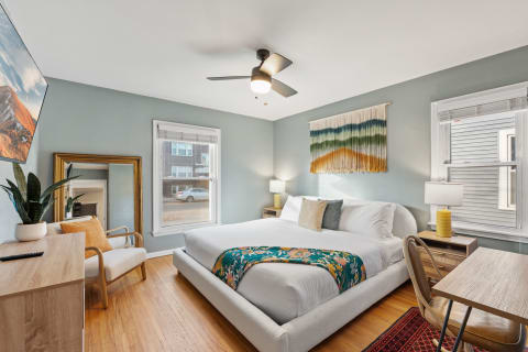 Bright and cozy bedroom featuring a plush bed with colorful throw and modern decor.