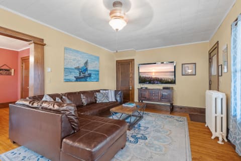 Cozy living room featuring a leather sofa, artwork, and a flat-screen TV.