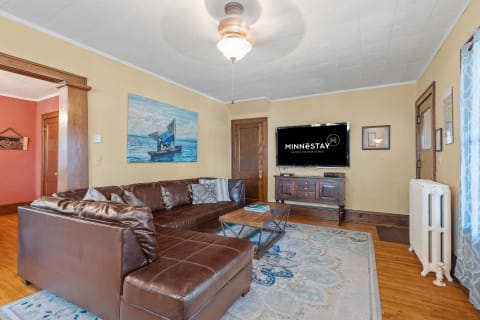 Living room featuring a leather sofa, a seascape painting, and a flat-screen TV.