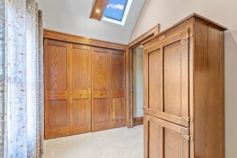 Interior view of a room with wooden wardrobes and elegant curtains by a window.