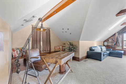 A cozy attic featuring a wooden desk, a seating area with a blue couch, and decorative elements on the walls.