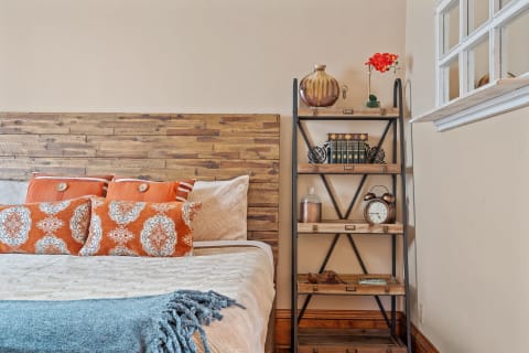 Cozy bedroom featuring a wood headboard, decorative pillows, and a bookshelf with various decor items.