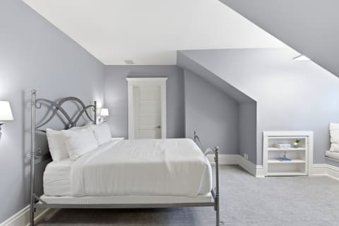 A serene bedroom with vaulted ceilings, a plush bed, and soft gray walls.