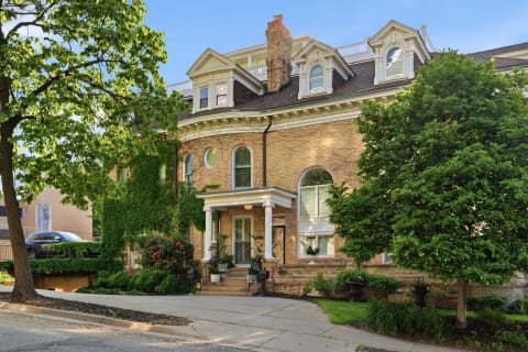 Historic brick building with ivy, inviting entrance, and lush greenery.