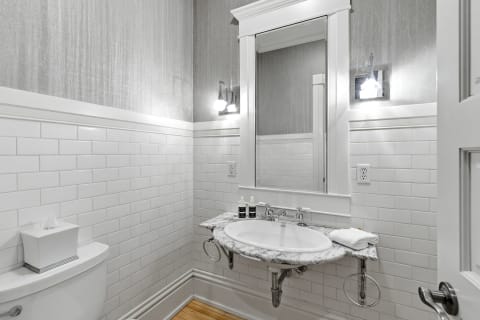 A stylish bathroom featuring white subway tiles, a marble sink, gray walls, and wooden flooring, creating a sophisticated atmosphere.