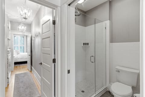 Contemporary bathroom with glass shower and elegant chandeliers.