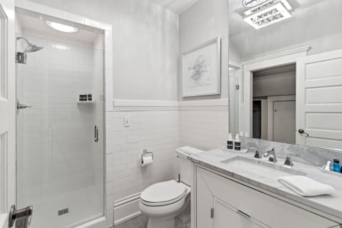 Bright bathroom with a walk-in shower, marble countertop, and modern fixtures.