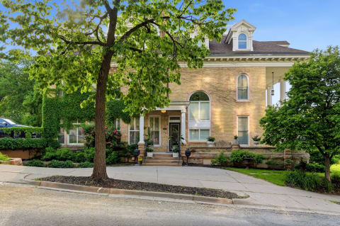 Historic brick building with lush landscaping and a grand entrance on a quiet street.