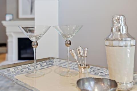 An elegant cocktail setup featuring crystal martini glasses, a polished shaker, and decorative cocktail picks on a stylish tray.
