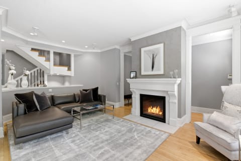 A modern living room with a plush sectional sofa, a white marble fireplace, and tasteful decor in gray tones.
