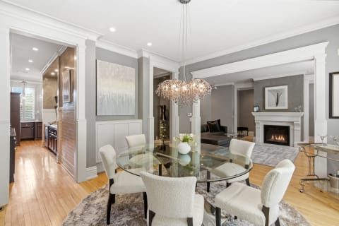 Sophisticated dining area featuring a glass table with plush chairs and a fireplace.