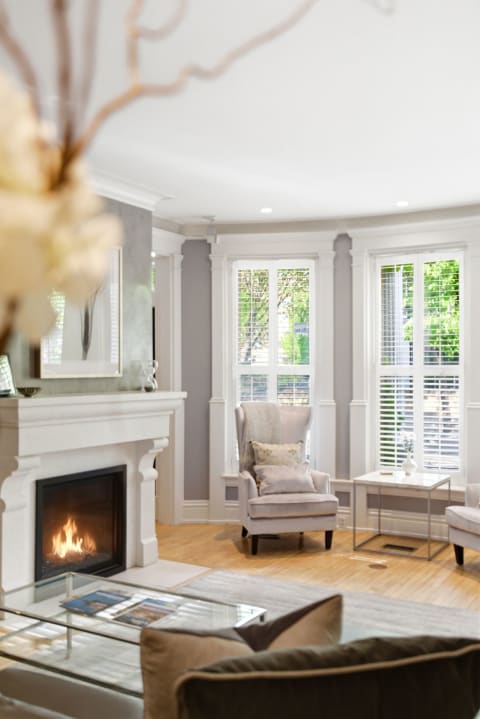 An elegant living room with a fireplace, bay windows, and comfortable seating.