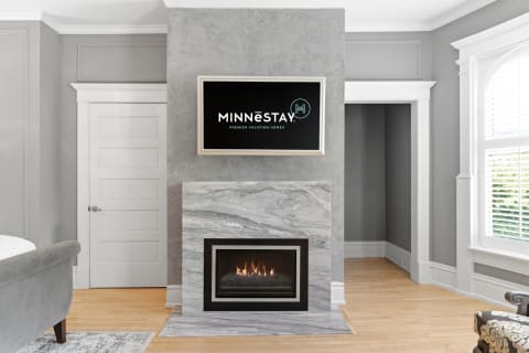A modern living room with a marble fireplace and television mounted above it, showcasing sleek design and comfort.