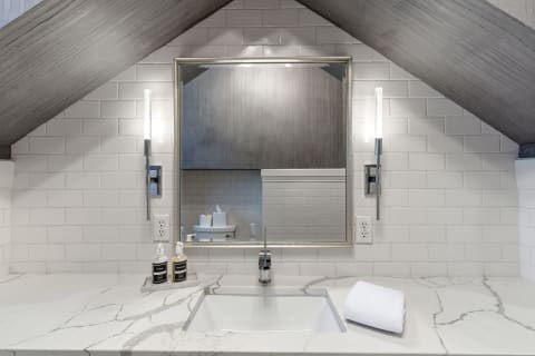 Stylish bathroom featuring a marble countertop, modern fixtures, and a vaulted ceiling.