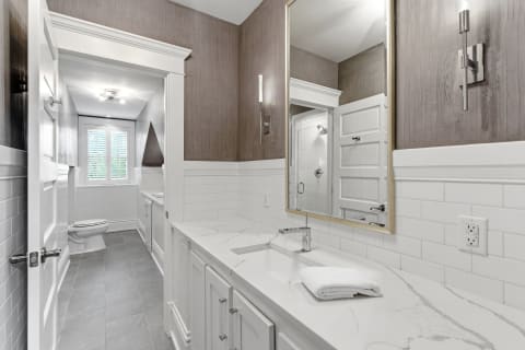 A modern bathroom with marble countertops, white subway tiles, and a wall mirror, showcasing an elegant design.