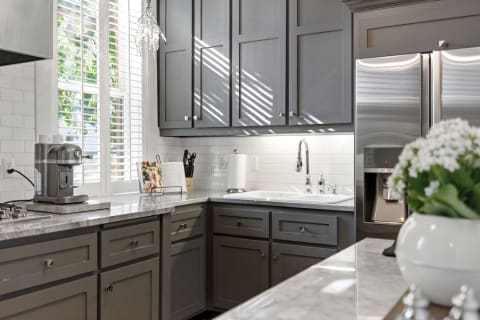 Modern kitchen featuring gray cabinets and marble countertops with natural light.