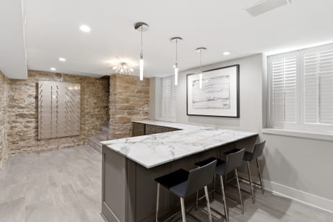 Modern kitchen with marble island, stone walls, and elegant lighting.