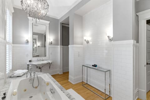 Elegant bathroom with crystal chandelier, marble tub, and subway-tiled walls.