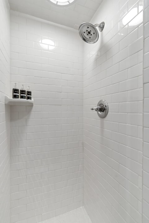 Bright white subway tiles and chrome fixtures in a pristine shower environment.