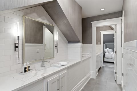 Bright and modern ensuite bathroom with marble countertops, subway tiles, and illuminated vanity.