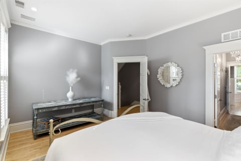 A serene bedroom featuring gray walls, hardwood floors, and elegant decorations.