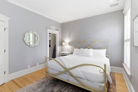 A calming bedroom featuring a vintage gold bed frame, white linens, and gentle lighting.