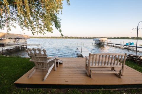 Serene lakeside scene featuring wooden seating and a dock.