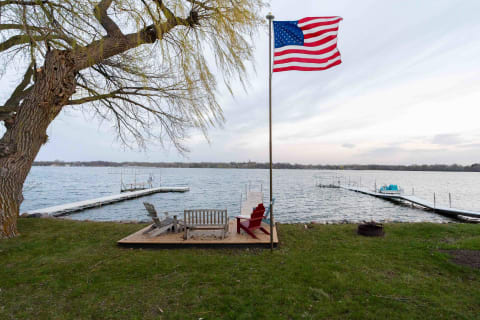 Lakeside view with a flag and wooden seating area.