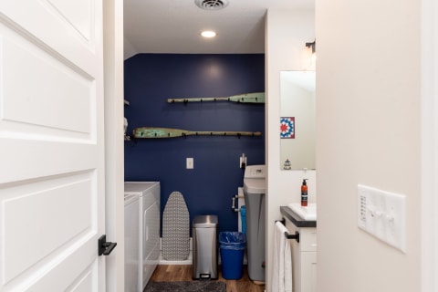 Laundry room featuring a navy blue wall, wooden paddles, and modern appliances.