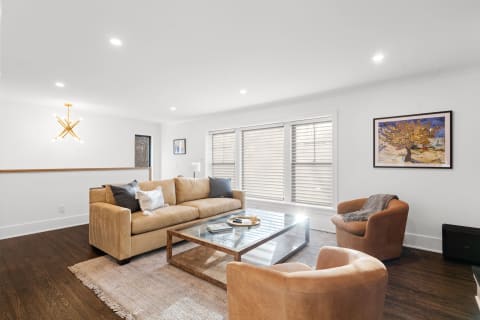 Stylish living room with a sectional sofa, glass coffee table, and vibrant wall art.