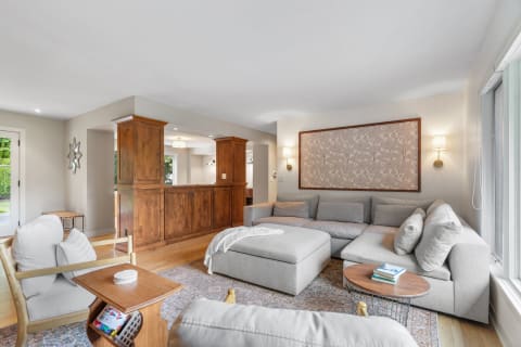 A modern living room featuring a gray sectional sofa, wooden cabinet, and natural lighting.