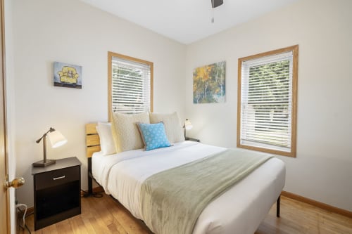Relax in your bright, airy bedroom with crisp linens and artwork. Two windows fill the space with natural light.