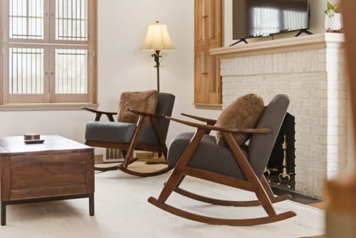 Unwind in your stylish living room featuring mid-century rocking chairs by the fireplace, where warm wood tones and soft lighting create the perfect retreat.