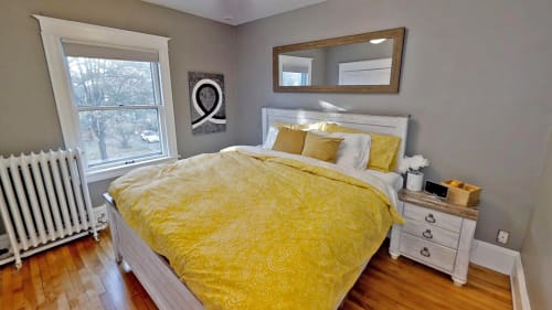 Wake up refreshed in your cozy bedroom featuring cheerful yellow bedding and warm hardwood floors that invite morning sunshine.