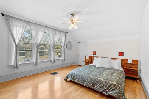 Your bright bedroom features warm hardwood floors, elegant curtains, and a ceiling fan for comfort.