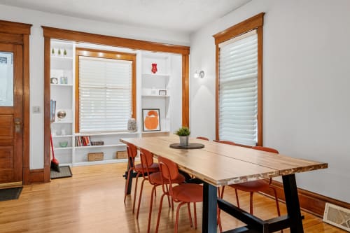 Gather around this handcrafted dining table where warm wood tones and built-in shelving create your perfect space for memorable meals together.