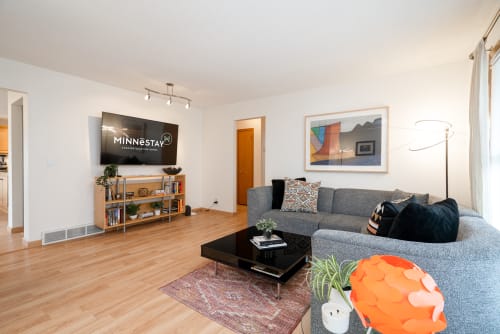 Settle into your stylish living space with cozy sectional seating, modern entertainment center, and warm hardwood floors throughout.