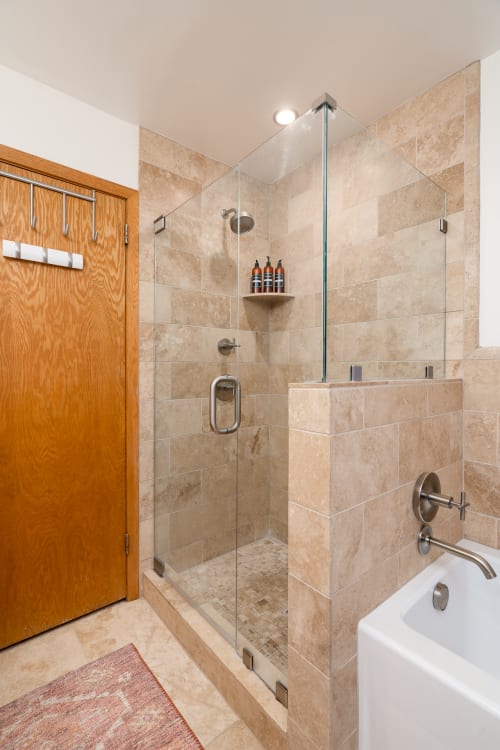 Step into your spa-like bathroom with elegant travertine tiles, spacious glass shower, and luxurious soaking tub for ultimate relaxation.