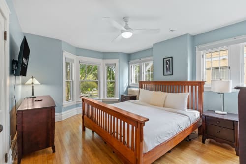 Your peaceful retreat features a comfortable bed, soothing blue walls, and bright windows that fill the space with natural light.