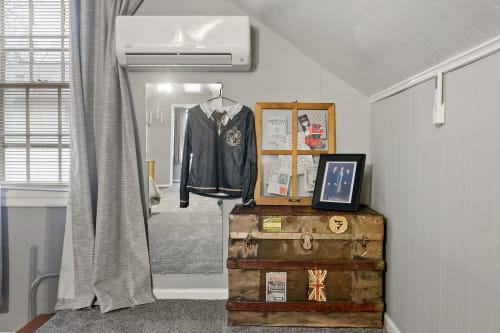 A vintage-inspired room corner with a trunk, framed photos, and a hanging shirt.