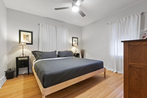 Sink into comfortable bedding in your peaceful bedroom retreat with warm wood floors and gentle ceiling fan breeze.