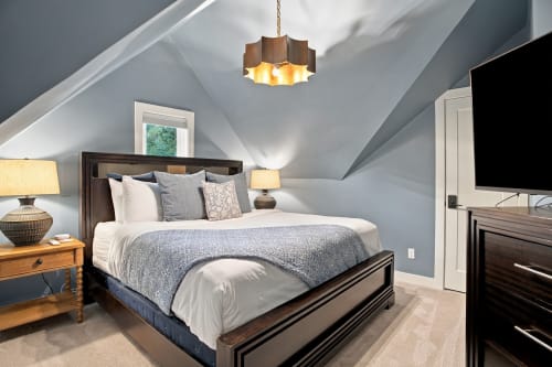 Sink into plush bedding beneath vaulted ceilings with warm lighting and a statement fixture. Your private master retreat awaits with cozy textures and charming details at every turn.