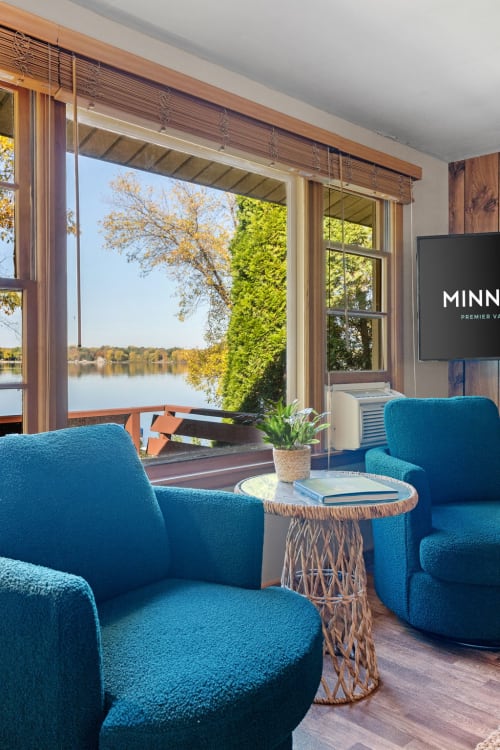 Sink into plush turquoise chairs while gazing at serene lake views through expansive windows—your perfect lakeside retreat awaits.