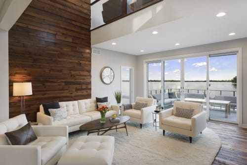 Relax in your stunning waterfront living room where modern elegance meets lakeside serenity through floor-to-ceiling windows.