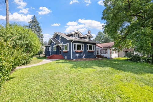 Charming blue craftsman home nestled in a quiet residential neighborhood with mature trees and spacious lawn.