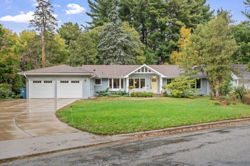 Charming single-story home nestled among mature trees in a peaceful residential neighborhood with convenient driveway parking.